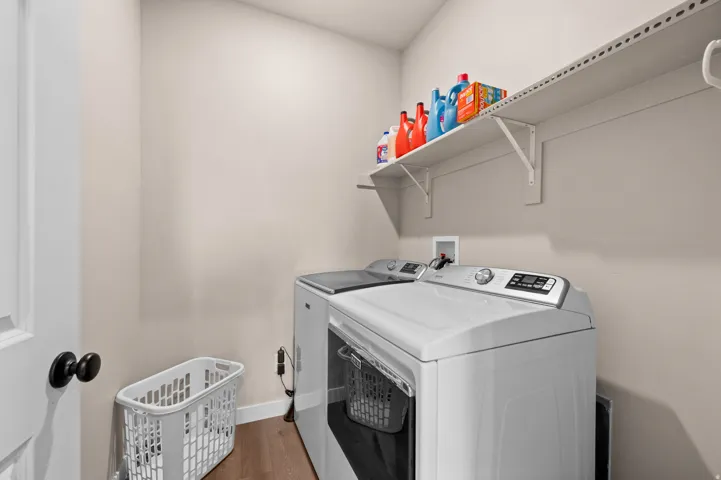 Dedicated laundry space with wood-finish flooring and wall-mounted shelving