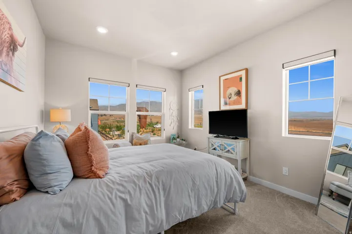 Carpeted flooring, recessed ceiling lighting, and multiple windows with roller shades