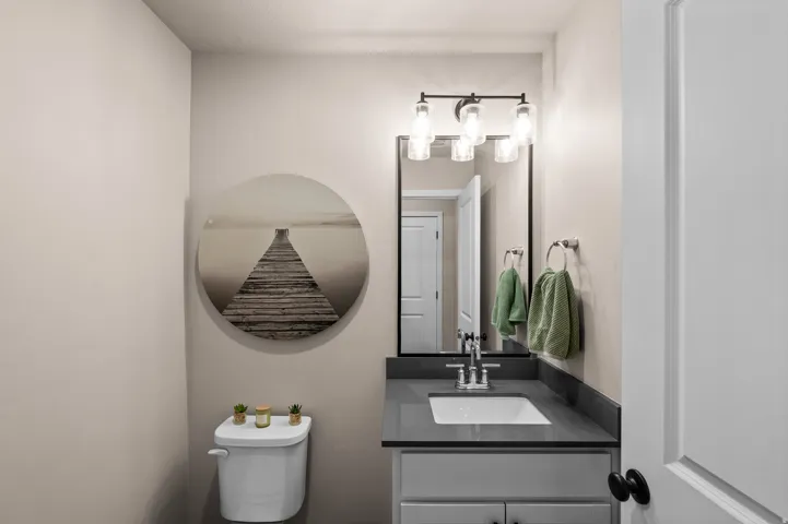 White vanity with a rectangular sink, dark countertop, and black-framed mirror