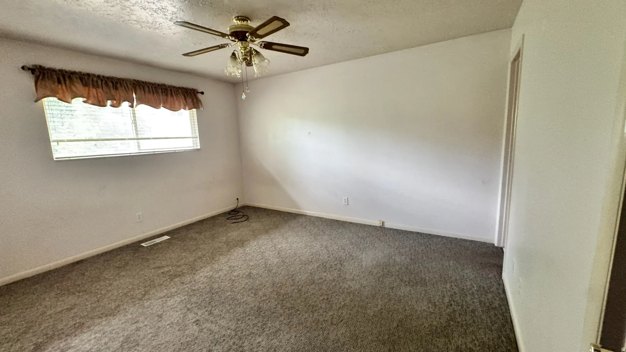 Carpeted room featuring a ceiling fan with light fixture and a window