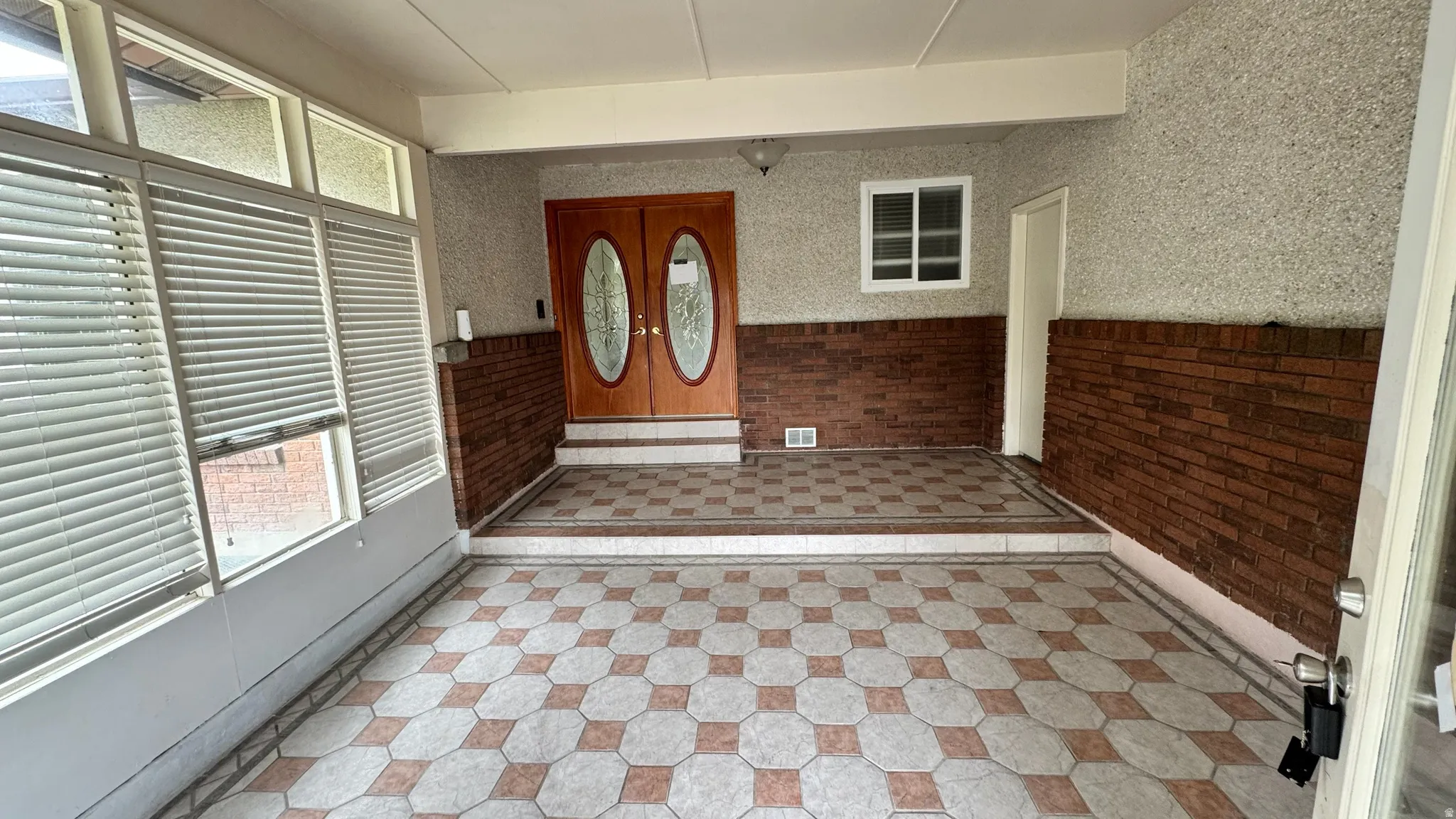 Enclosed patio with geometric tile flooring and exposed brick accents