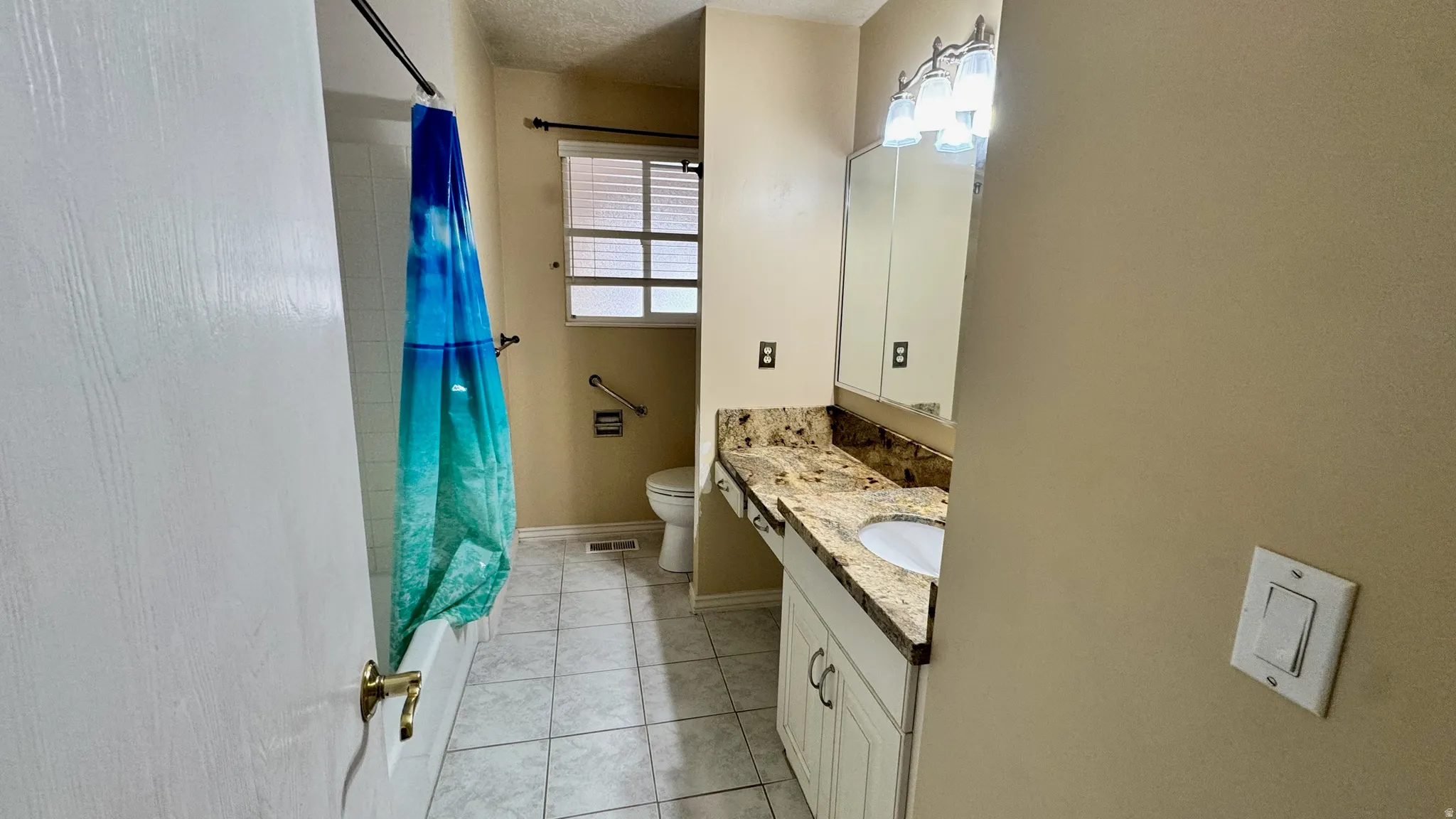 Bathroom featuring a vanity with an integrated sink, a stone-finish countertop, tile flooring, and a built-in bathtub with shower