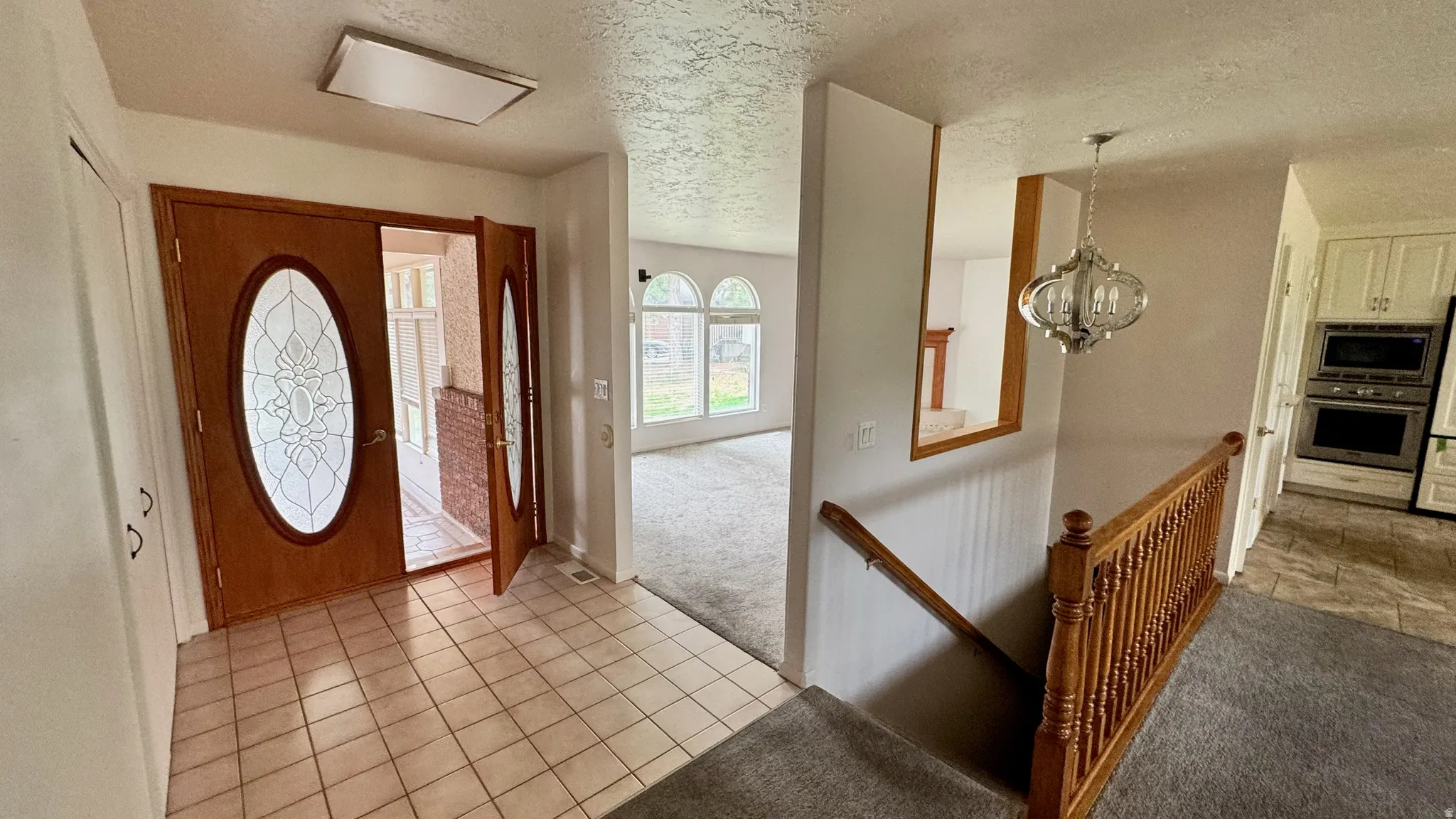 Entryway with tile flooring and double wood-finish doors featuring decorative glass inserts