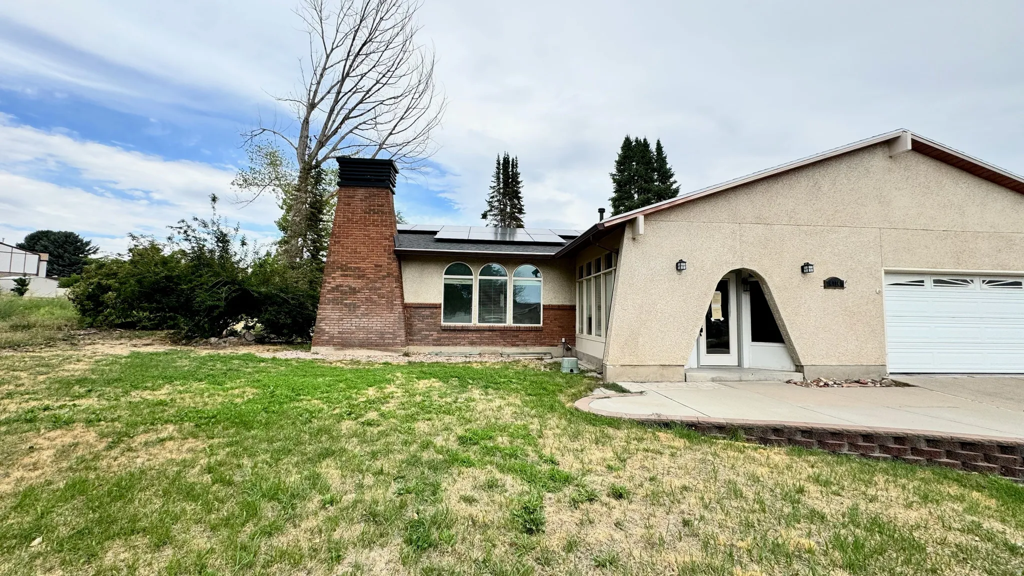 Stucco exterior with a brick-clad chimney and solar panels