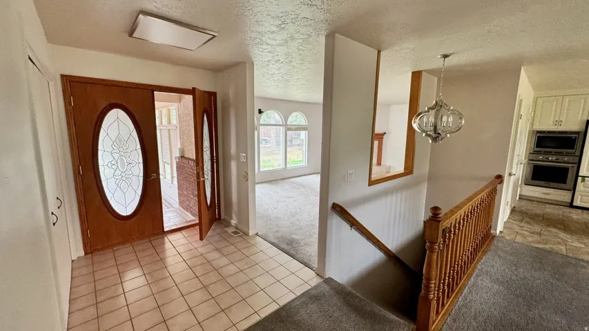 Entryway with tile flooring and double wood-finish doors featuring decorative glass inserts