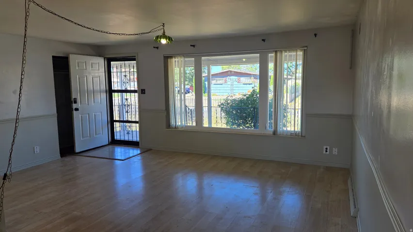 Wood-finish flooring with wainscoting and a large front-facing window
