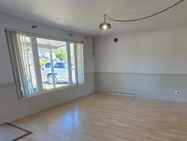 Wood-finish flooring throughout, bay window with vertical blinds, and two-tone wall treatment