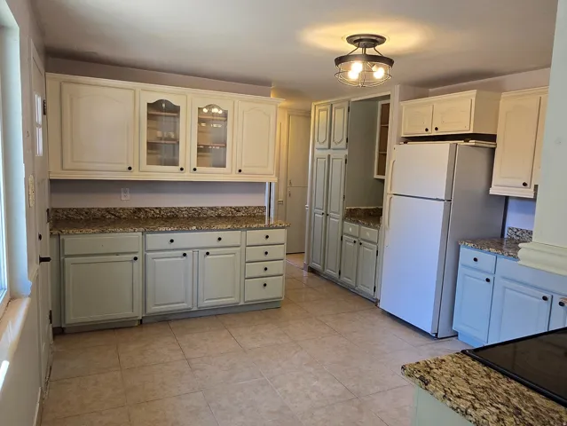 Kitchen featuring tile flooring, white cabinetry, light countertops, and ceiling-mounted light fixtures