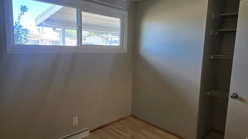 Bedroom #4 Wood-finish flooring with a window and a built-in closet featuring shelving