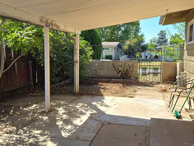 Covered patio area with concrete flooring and mature rose bushes.