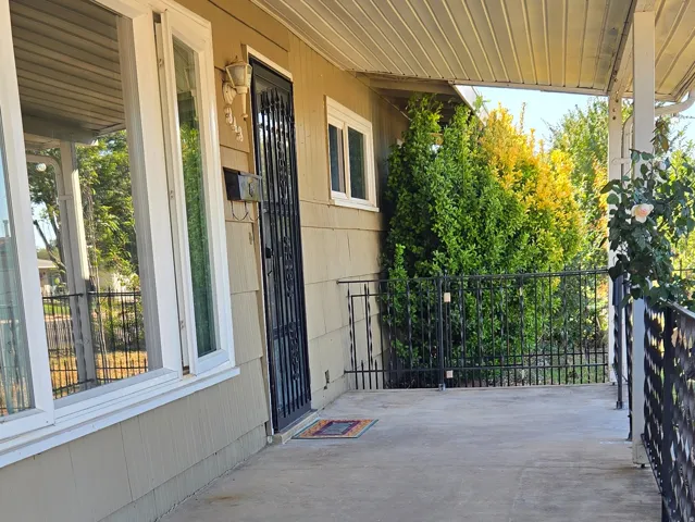 Covered front porch with concrete flooring and a screen door