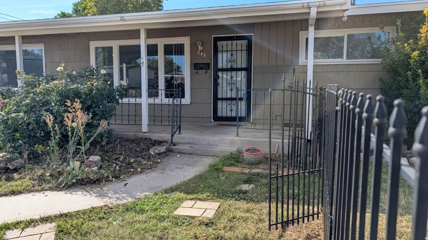 Siding exterior with multiple windows, a covered entry, and a wrought iron fence with gate