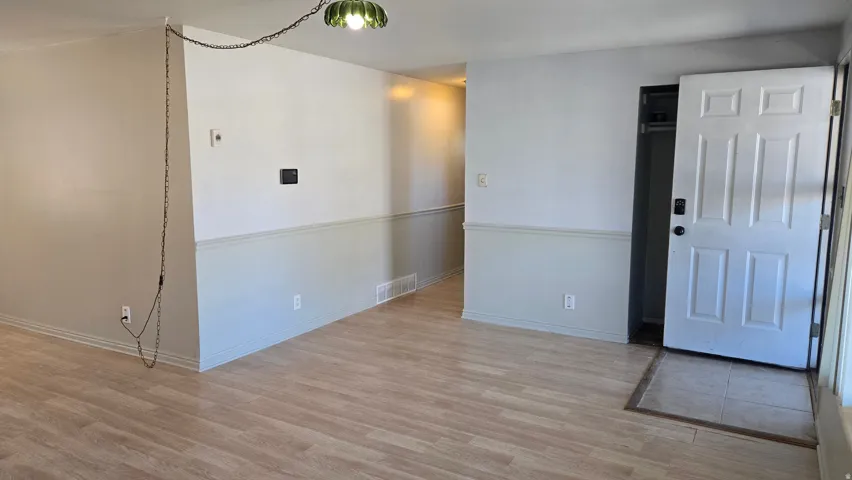 Wood-finish flooring, two-tone painted walls with chair rail molding, and a paneled entry door with a digital lock