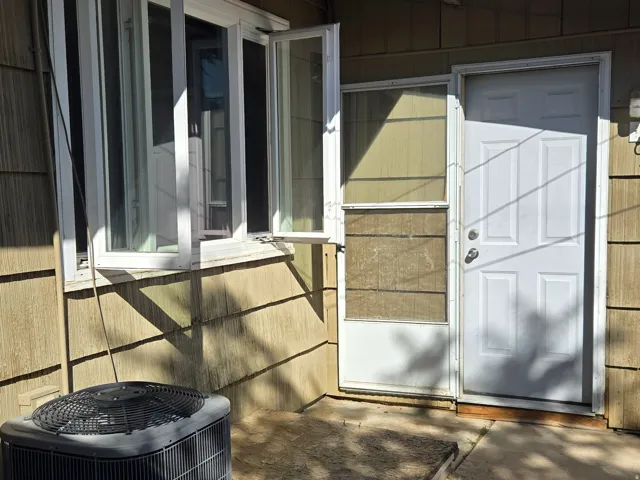Exterior wall with horizontal siding, white frame windows, laundry room door, and an outdoor HVAC unit