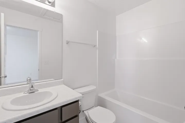 Bathroom featuring a vanity with a laminate countertop, undermount sink, chrome faucet, and a toilet