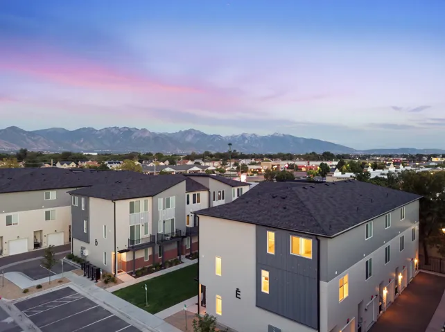 Contemporary multi-story townhomes with dark asphalt shingle roofs and light-toned siding