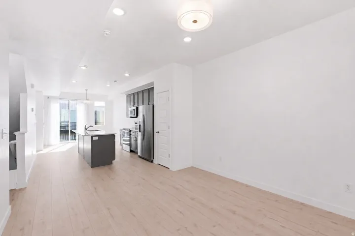 Open-concept living area featuring light wood-finish flooring, recessed lighting, and a contemporary kitchen with stainless steel appliances