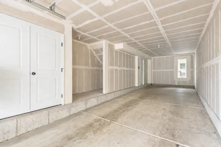 Garage space featuring unfinished drywall, concrete flooring, and a single window