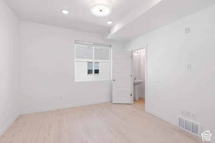 White walls with wood-finish flooring, recessed lighting, and a modern flush-mount light fixture