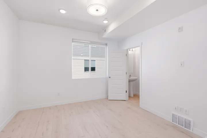 White walls with wood-finish flooring, recessed lighting, and a modern flush-mount light fixture