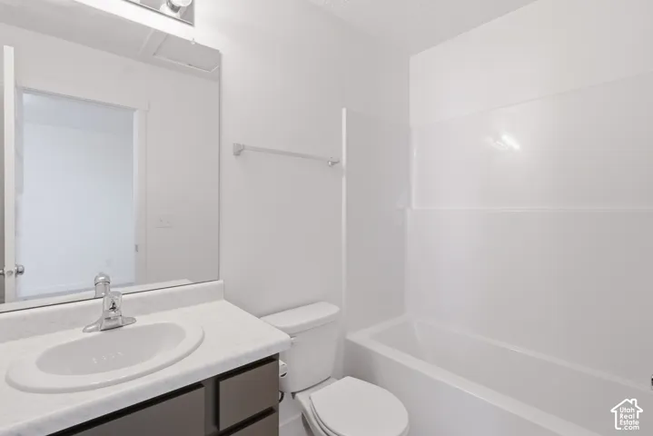 Bathroom featuring a vanity with a laminate countertop, undermount sink, chrome faucet, and a toilet