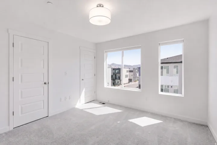 Spacious room with plush gray carpeting, white trim, and two paneled doors
