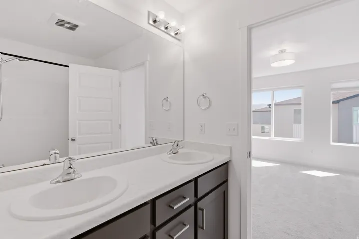 Double vanity with undermount sinks, chrome fixtures, and dark wood-finish cabinetry