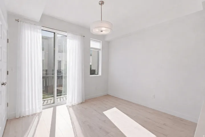 Light wood-finish flooring, white walls, and a contemporary ceiling fixture