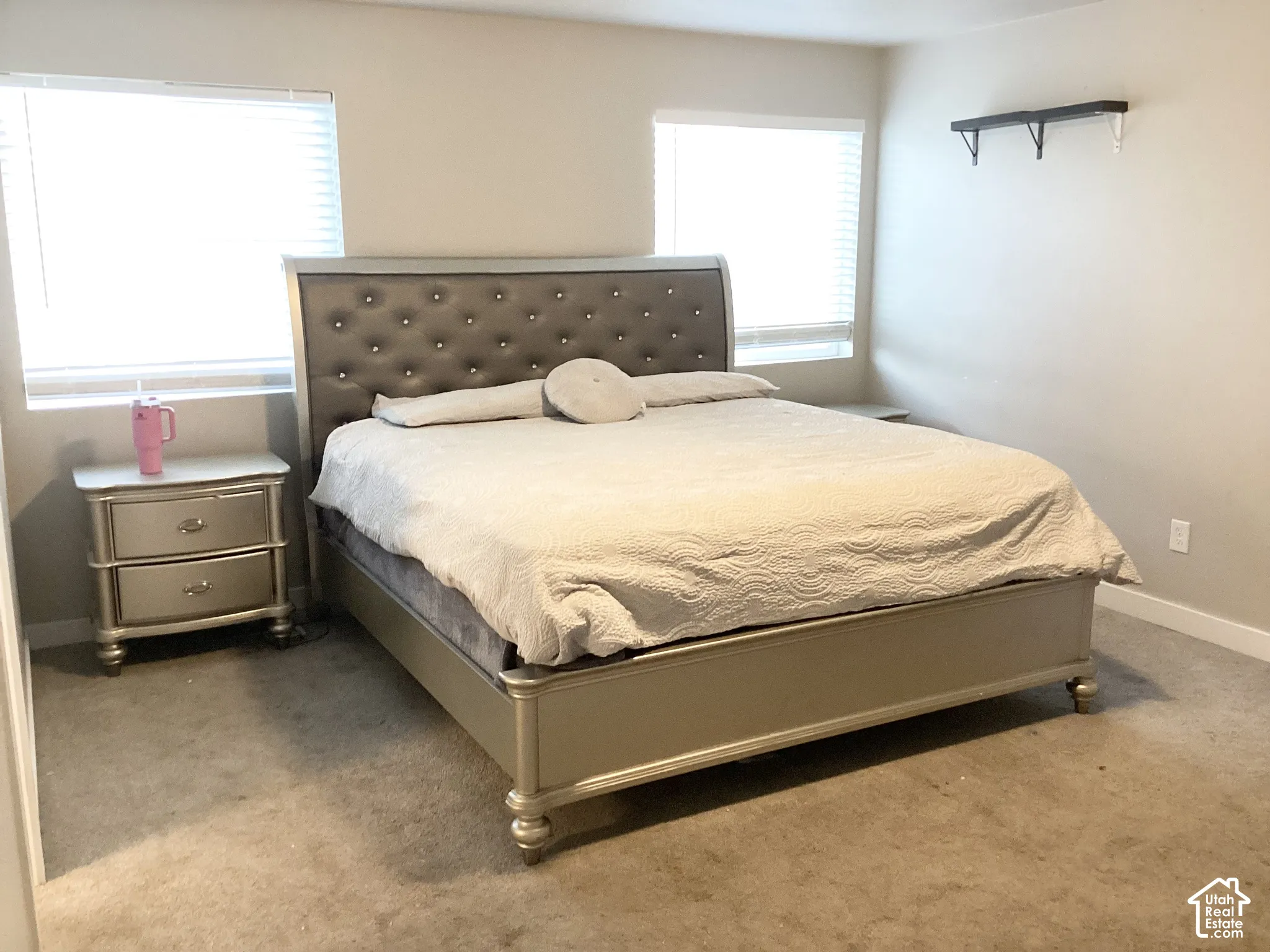Two windows with blinds, built-in wall shelving, and neutral wall paint