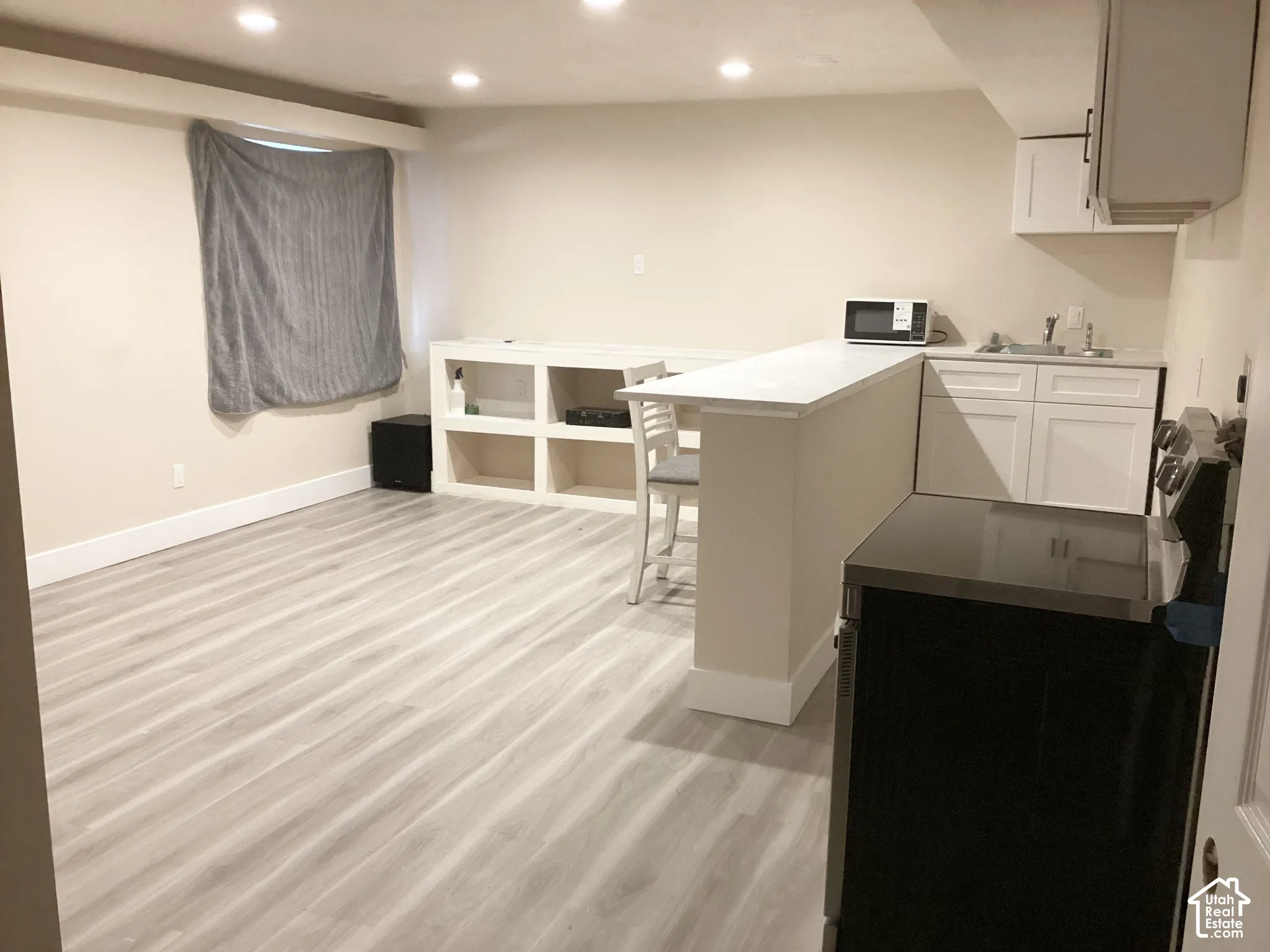 Recessed lighting, wood-finish flooring, built-in shelving, white cabinetry, and a kitchen counter