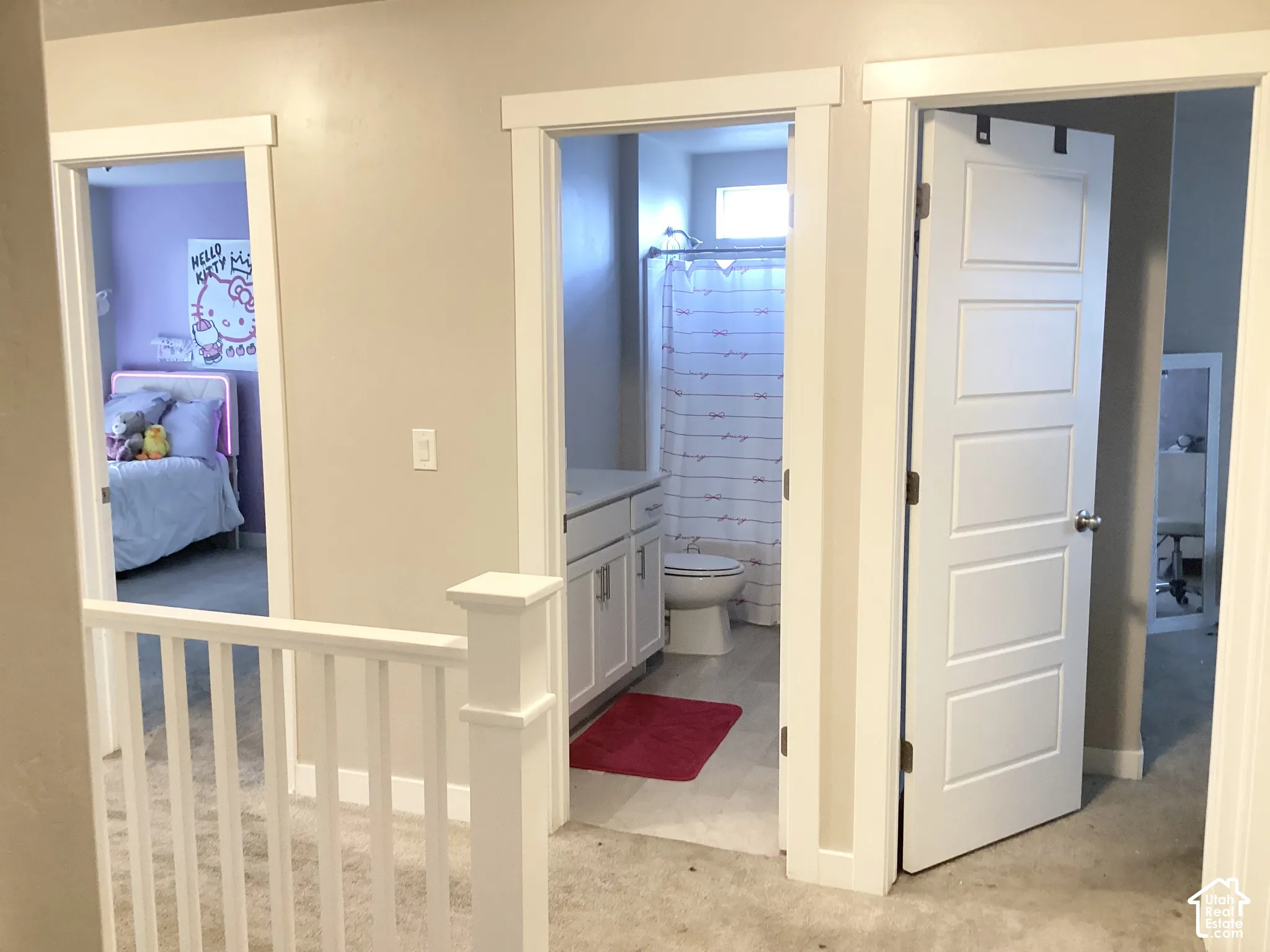 White baluster railing system, white shaker-style vanity with countertop, white panel doors, and a sliding barn door hardware system