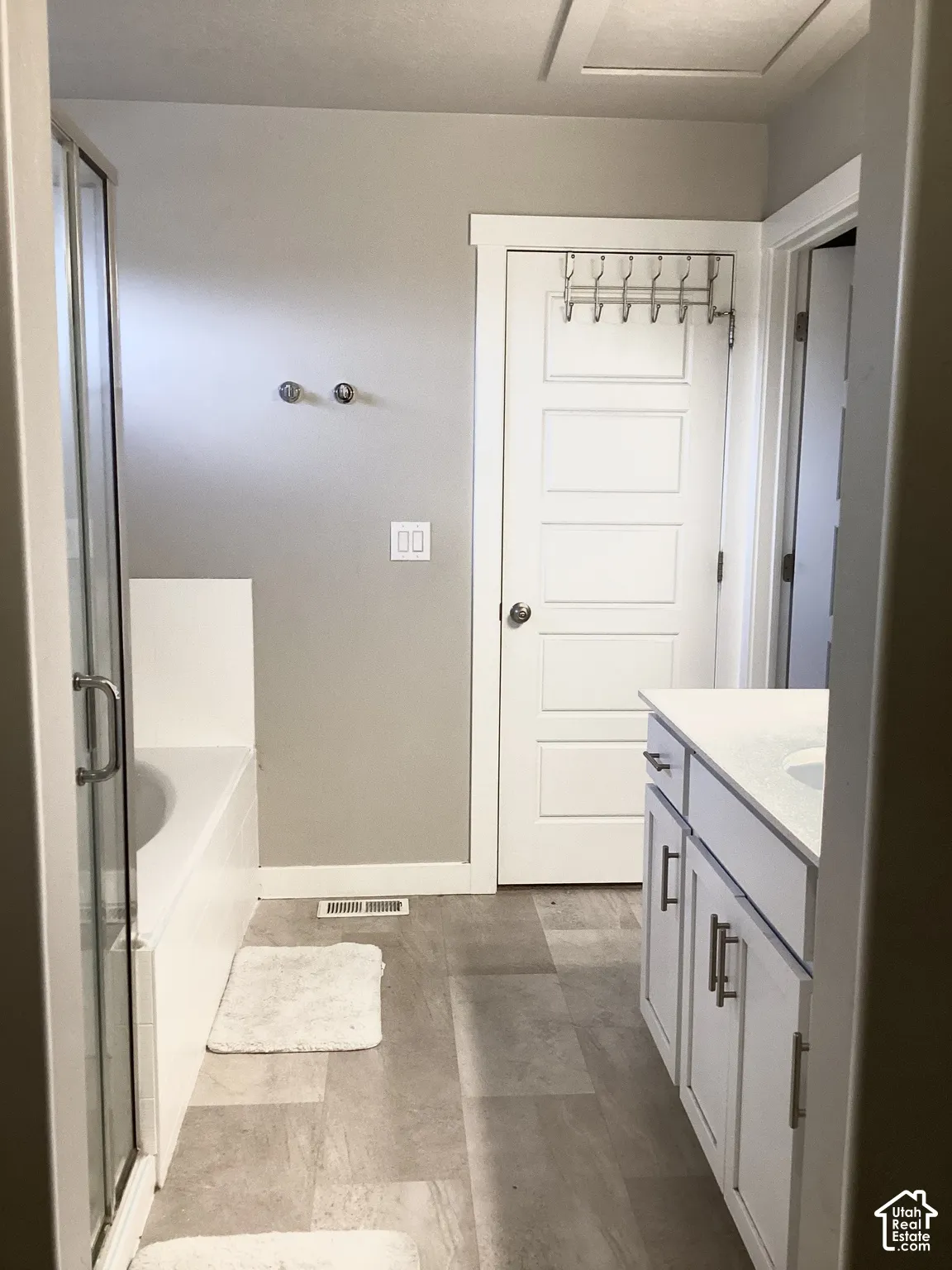White vanity with undermount sink, light-toned stone-finish countertop, and dark-finish hardware