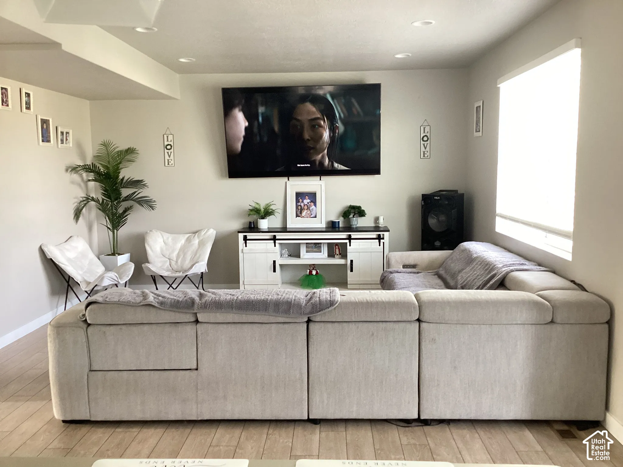 Light wood-finish flooring, recessed lighting, built-in window with roller shade, and a media console with sliding barn door accents