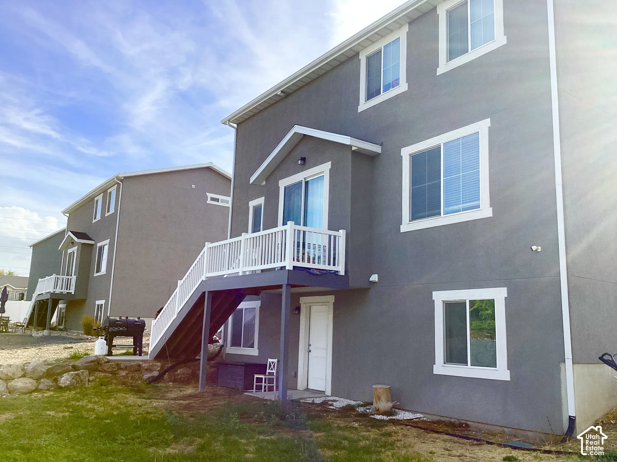 Stucco exterior with white trim windows and a white baluster deck