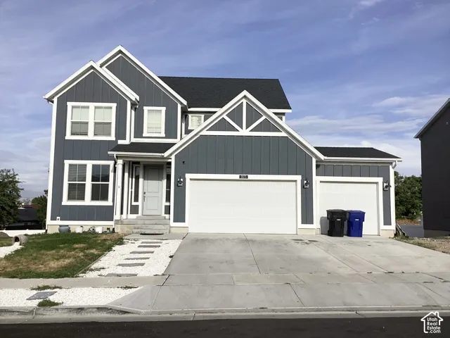 Board and batten siding, multiple gables, white trim accents, attached two-car garage, and a concrete driveway