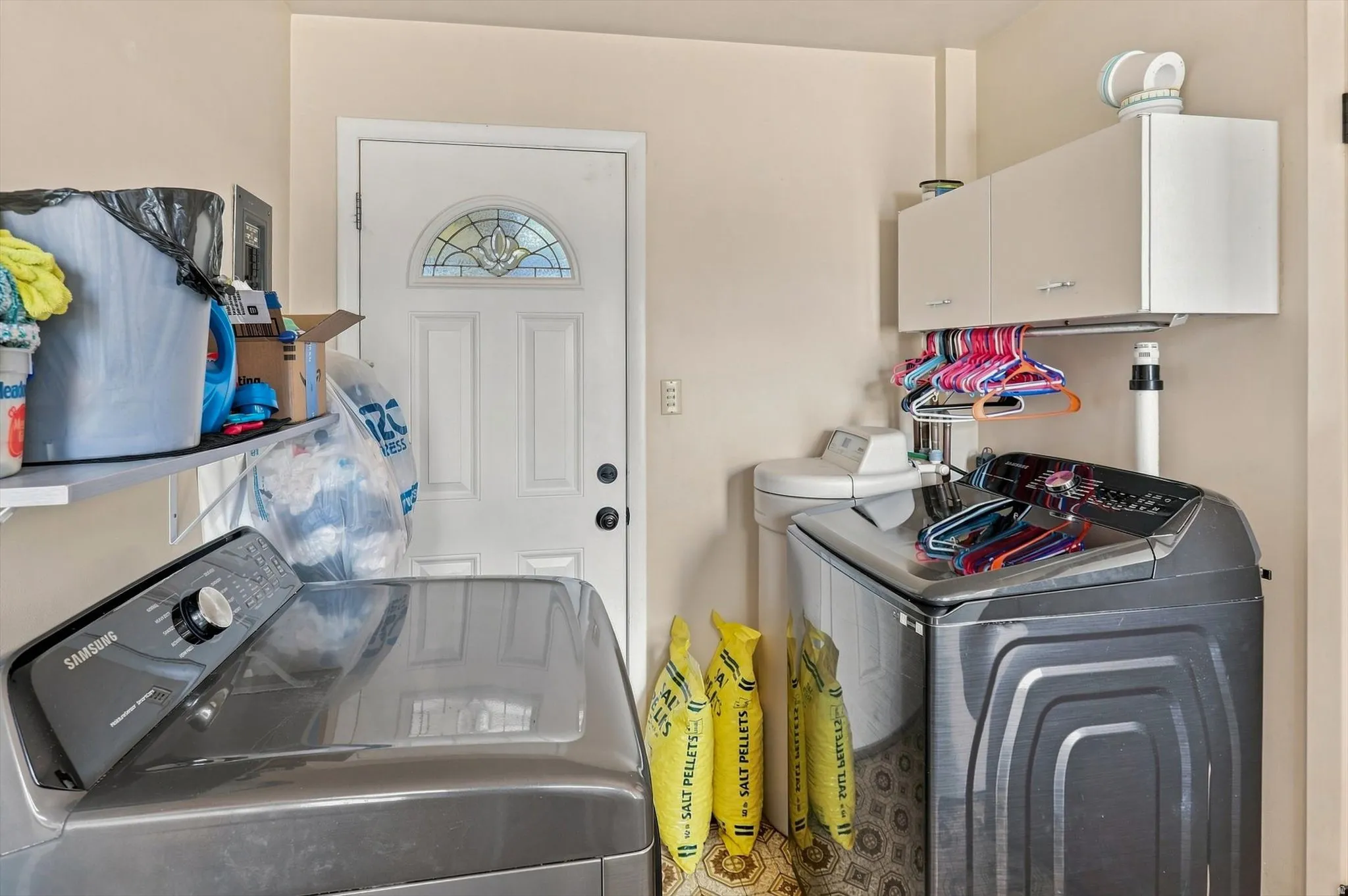 Utility room featuring a white paneled door with a stained glass transom, floating wall shelving, and wall-mounted cabinetry