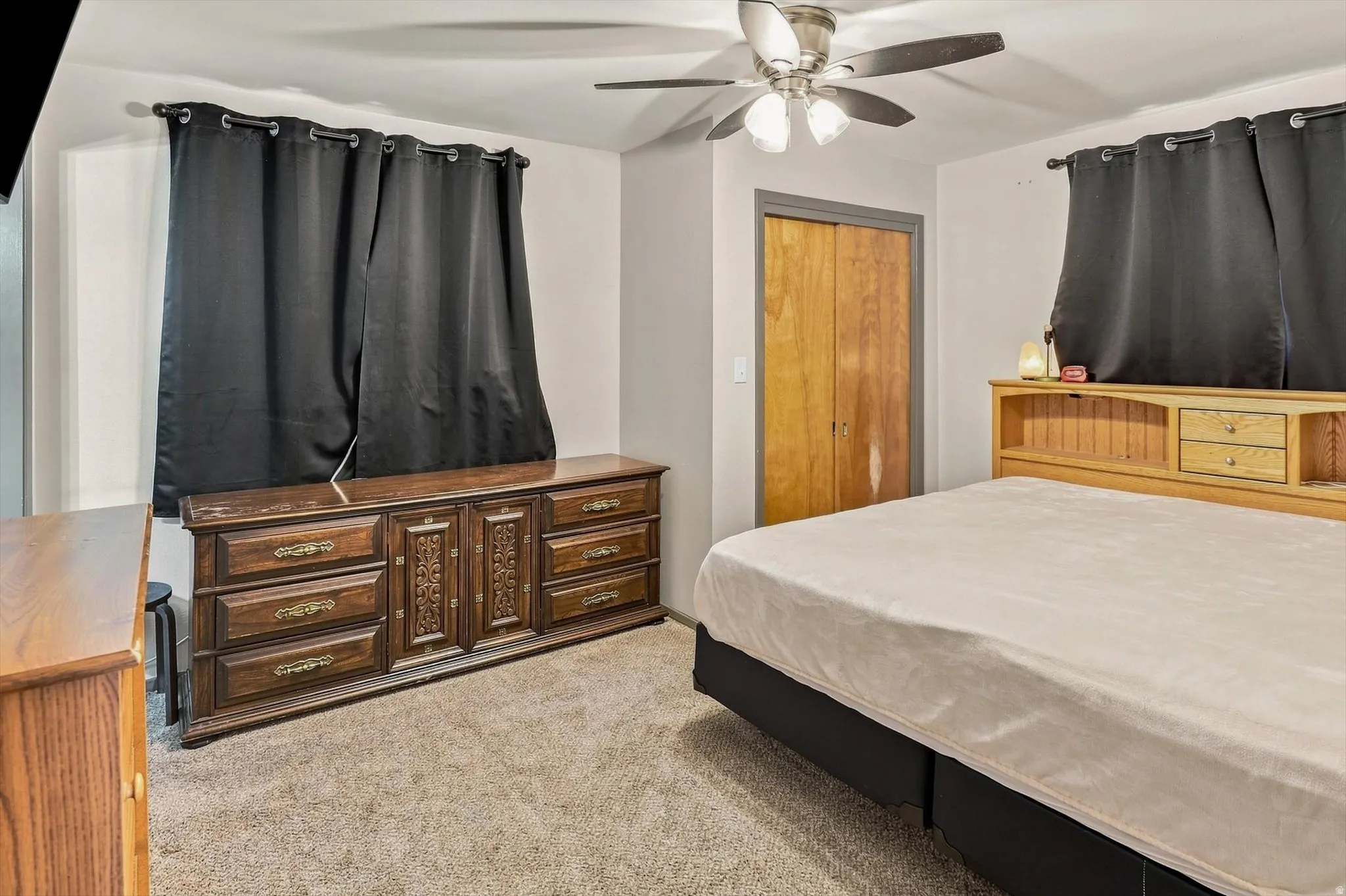 Carpeted flooring, ceiling fan with integrated lighting, and a closet with bi-fold wood doors