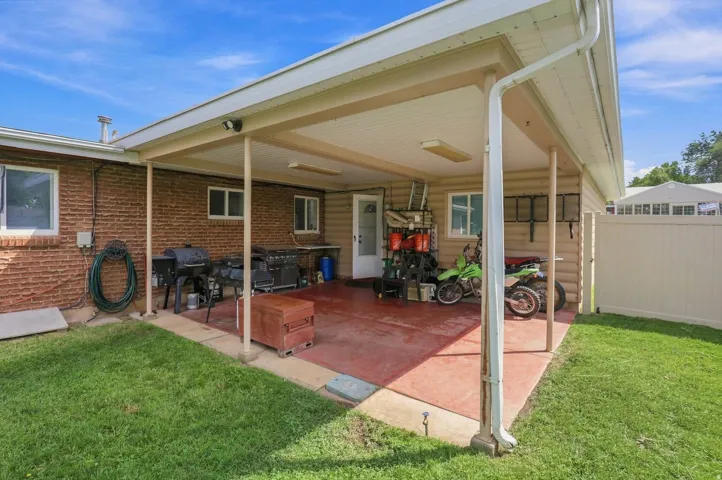 Covered patio with a concrete surface, brick exterior, and a white privacy fence