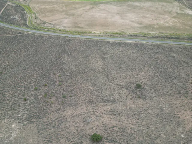 Expansive undeveloped land featuring natural shrubbery and a paved road