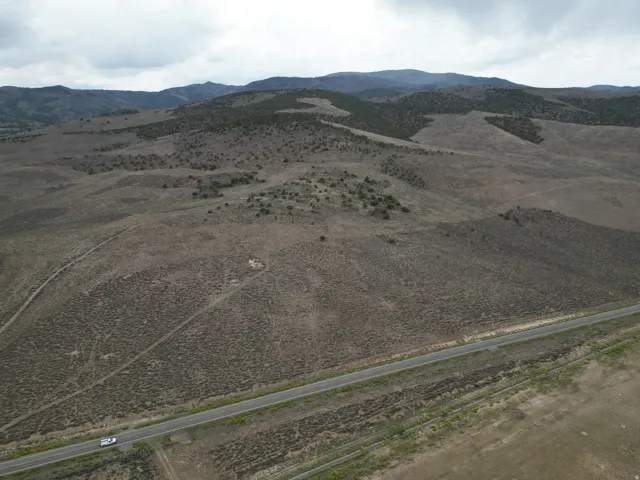Expansive rural landscape featuring a paved road, natural terrain, and distant hills