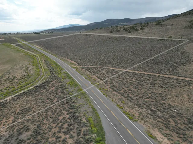 Paved road access, expansive undeveloped land, distant mountainous terrain, and clear boundary lines