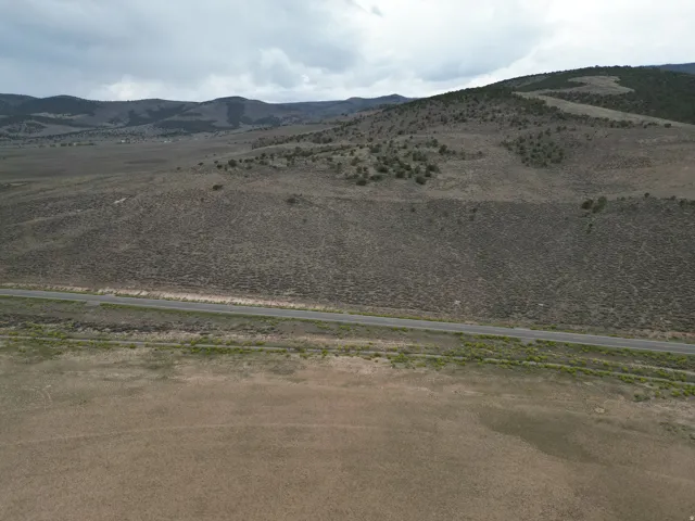 Expansive rural landscape featuring a paved road, rolling hills, and scattered vegetation