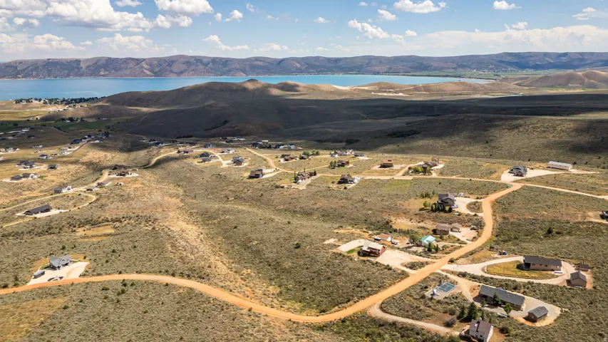 Expansive elevated landscape featuring scattered residential properties, winding unpaved roads, and distant water