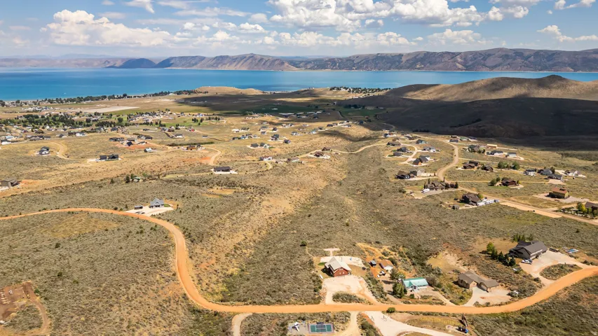 Expansive land with scattered homes, a natural terrain, and distant water body