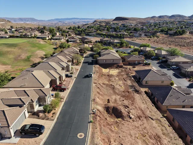 Residential street featuring multiple single-story properties with tan stucco exteriors and tile roofs