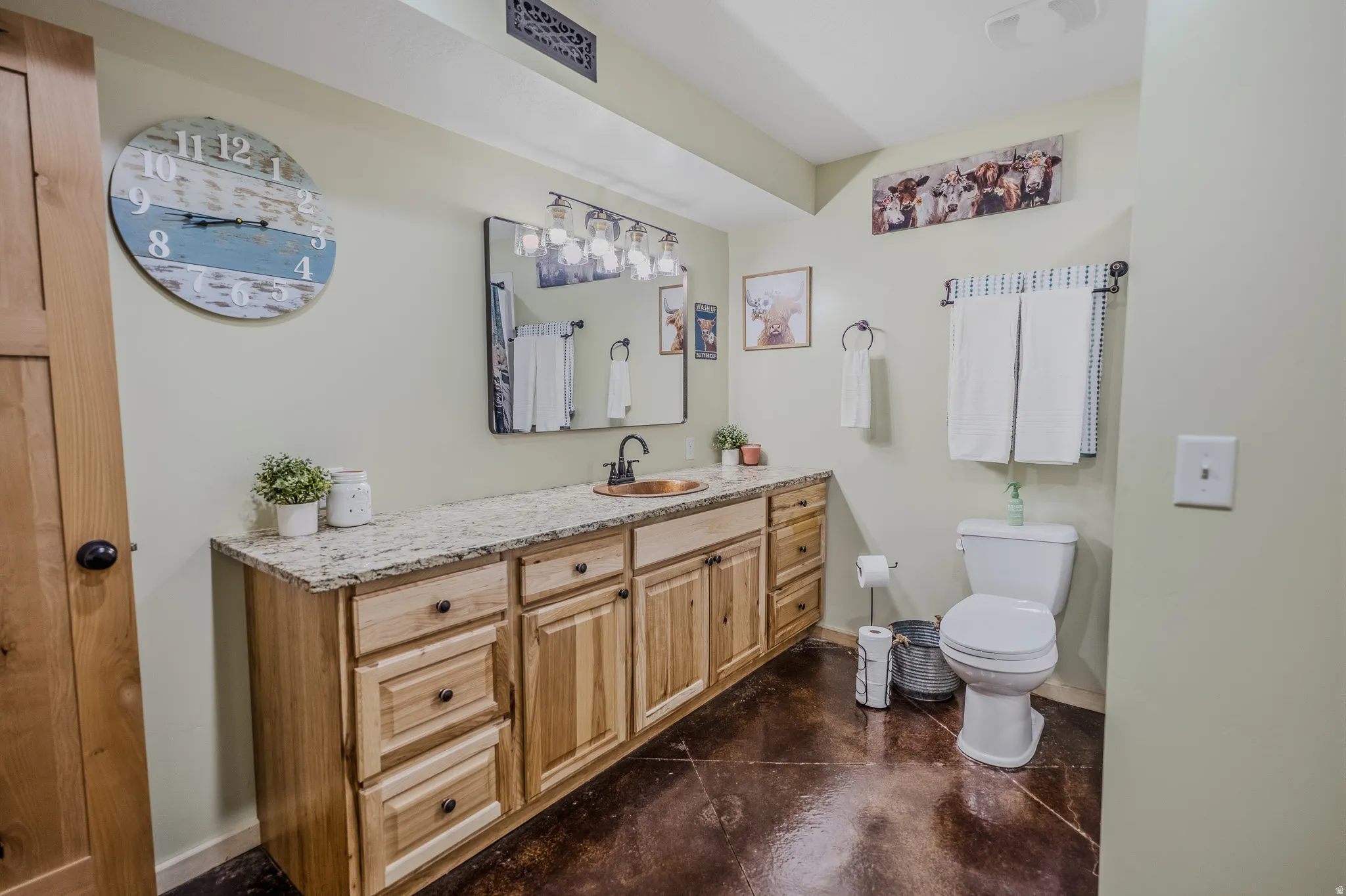 Long wood-finish vanity with an undermount sink, granite-style countertop, and dark-framed mirror