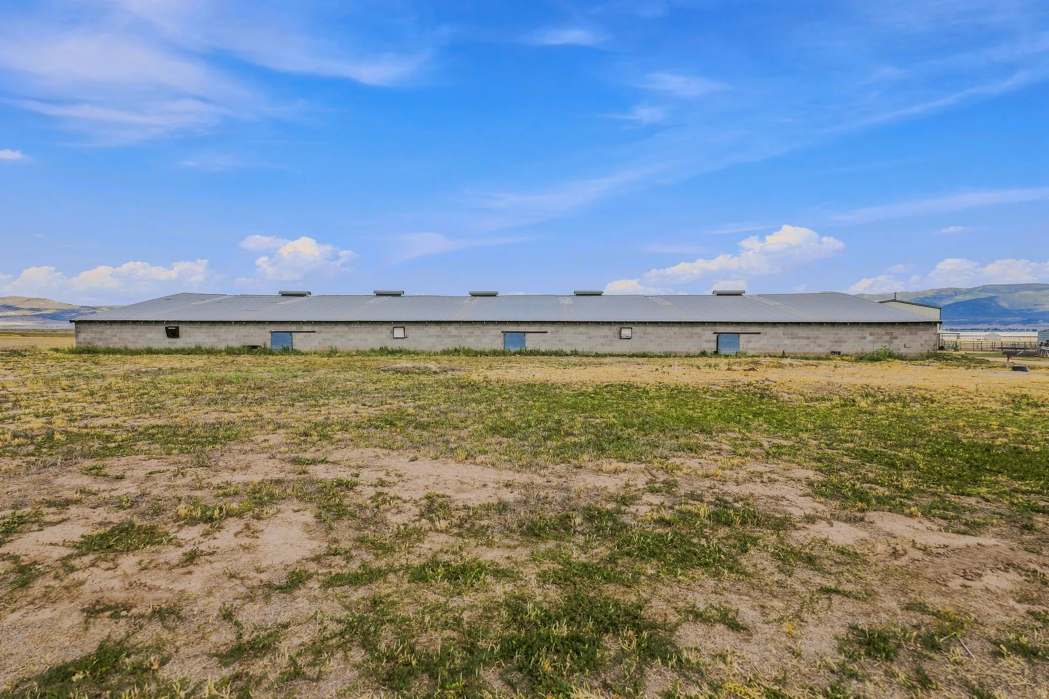 Spacious agricultural building with a metal roof, multiple access doors, and a large open field
