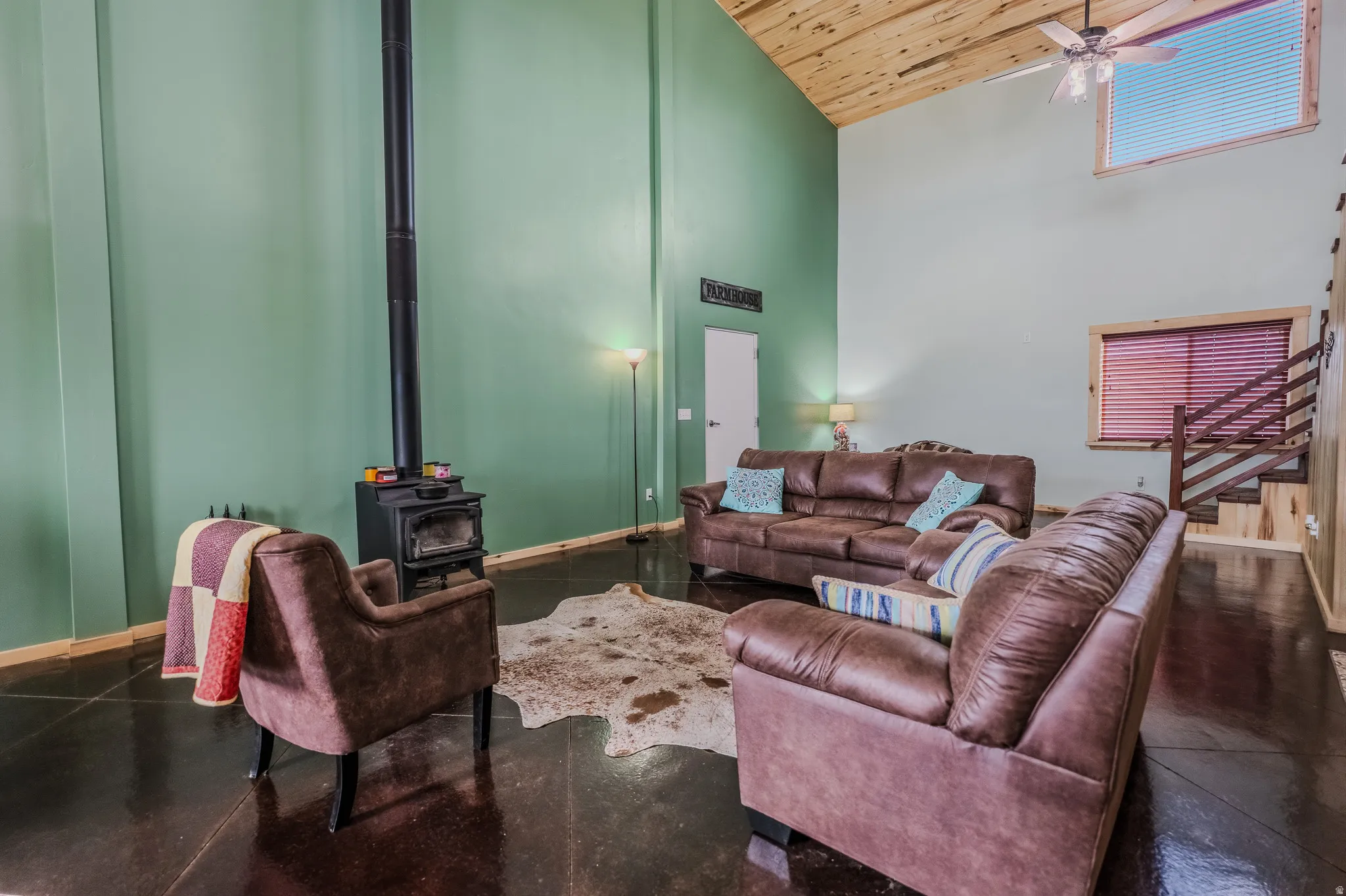 Vaulted wood-paneled ceiling, exposed wood staircase, wood-burning stove, high windows, and polished concrete flooring