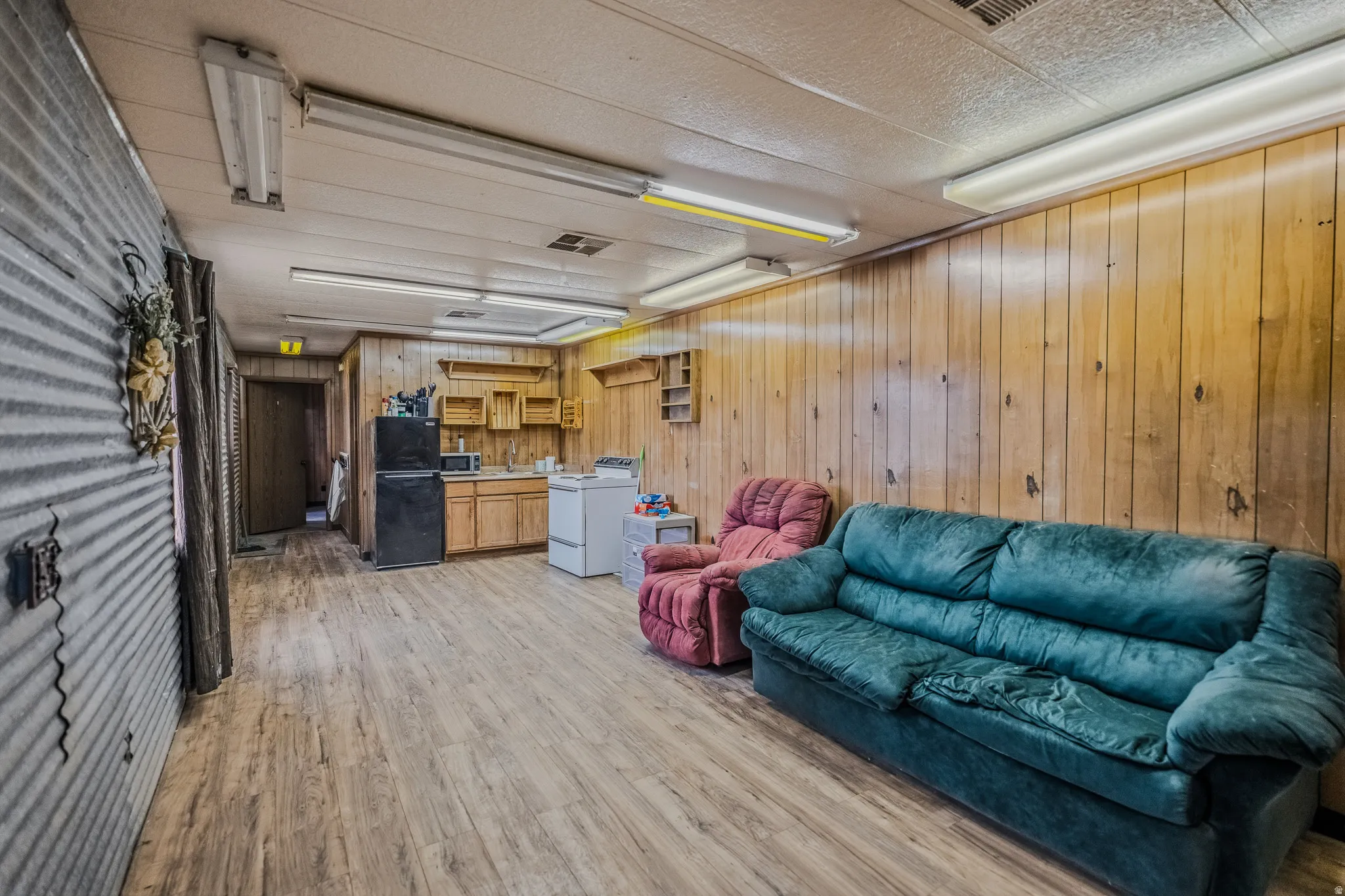 Wood-finish flooring throughout, wood paneling, and fluorescent ceiling lights