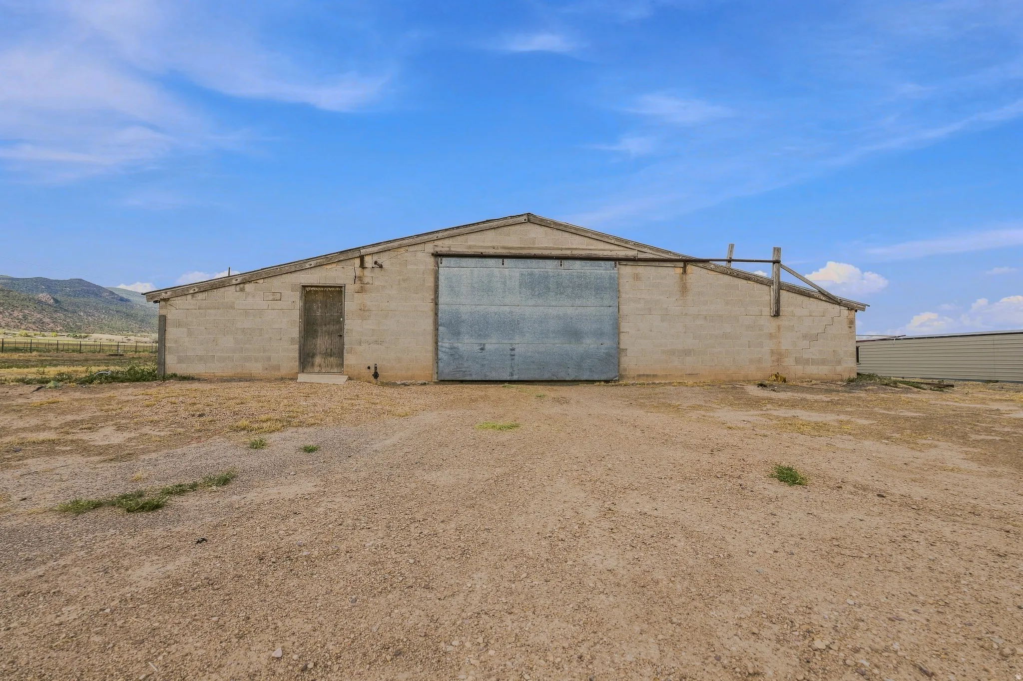 Concrete block structure with a corrugated metal sliding door, a side entry door, and a pitched roof